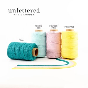 May include: Four spools of cotton cord in teal, robin's egg blue, powder pink, and pineapple yellow. The spools are arranged in a row on a white background. The text "Unfettered Art & Supply" is at the top of the image.