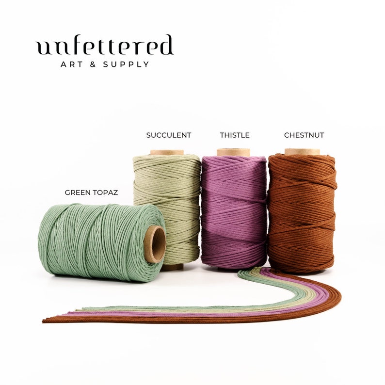 May include: Five spools of cotton cord in different colors: green topaz, succulent, thistle, chestnut. The cord is arranged in a row with the ends of the cord trailing off to the right.
