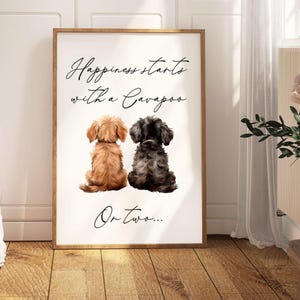 May include: A white canvas print with a brown wooden frame. The print features a black and brown dog and a brown and white dog sitting back to back. The text "Happiness starts with a Cavapoo on two..." is printed on the canvas.