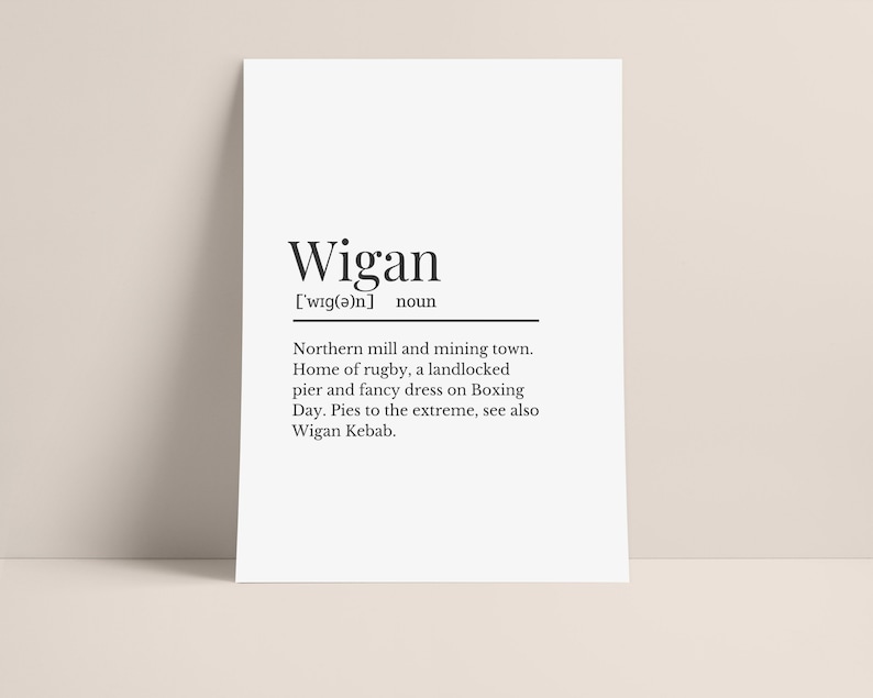May include: A black and white printable poster with the definition of the word "Wigan". The definition reads: "Northern mill and mining town. Home of rugby, a landlocked pier and fancy dress on Boxing Day. Pies to the extreme, see also Wigan Kebab."