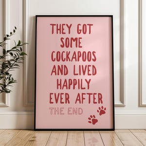 May include: A framed pink print with the text "THEY GOT SOME COCKAPOOS AND LIVED HAPPILY EVER AFTER THE END" in red lettering. Two red paw prints are at the bottom. The frame is black.