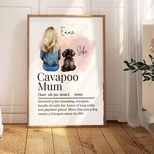 May include: A watercolour illustration of a woman with blonde hair and a dog. The woman is wearing a blue denim jacket and jeans. The dog is a black cavapoo. The text "Emma" and "Suki" are written above the woman and dog, respectively. The text "Cavapoo Mum" is written in large letters below the woman and dog. The text "[kav- uh-pu: mʌm] noun" is written below the text "Cavapoo Mum". The text "Devoted to her bounding, energetic, bundle of curly fur. Lover of long walks and playtime galore. More than just a dog owner, a Cavapoo mum for life!" is written below the text "[kav- uh-pu: mʌm] noun".