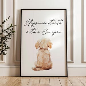 May include: A framed print with a watercolour illustration of a Cavapoo dog, seen from behind. The print includes the text "Happiness starts with a Cavapoo" in cursive script. The artwork is set against a white background.