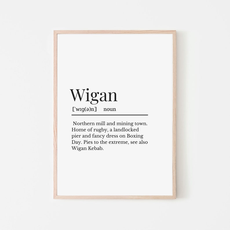 May include: A black and white printable art print with the word "Wigan" defined as a northern mill and mining town, home of rugby, a landlocked pier, and fancy dress on Boxing Day. The print also mentions Wigan Kebab.