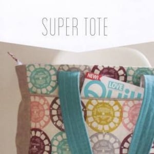 May include: A large tote bag with teal straps and a zipper closure. The bag is made of a white fabric with a colorful pattern of circles. The bag has a pocket on the front with a magazine inside. The magazine has the words "New!" and "Love" on the cover. The bag is labeled "Super Tote" and "#531".