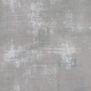 May include: A textured fabric with a distressed, industrial aesthetic. The surface is primarily gray, with areas of white and subtle hints of blue-green. The design features a worn, weathered appearance, suggesting a vintage or rustic style. Ideal for quilting or crafting projects.