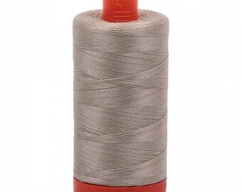 May include: A spool of tan thread with a bright orange top and base. The thread is tightly wound around the spool, creating a cylindrical shape. The thread appears to be a neutral color, suitable for various sewing projects.