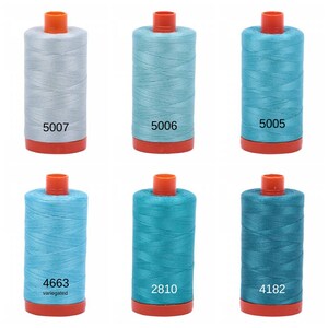 Puede incluir: Seis carretes de hilo en varios tonos de azul y gris. Los carretes est&aacute;n etiquetados con los n&uacute;meros 5007, 5006, 5005, 4663, 2810 y 4182.