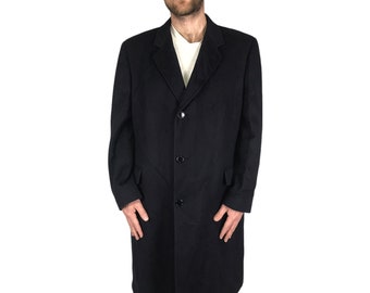 May include: A long black wool coat with a single-breasted closure and three buttons. The coat has a classic design and a tailored fit.