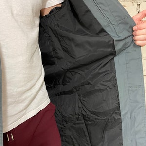 May include: A gray long-sleeved jacket with a black lining. The jacket is open and the lining is visible.