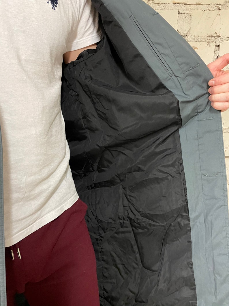 May include: A gray long-sleeved jacket with a black lining. The jacket is open and the lining is visible.