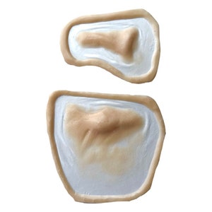 Puede incluir: Dos moldes de silicona beige para crear heridas falsas. Los moldes tienen forma de un peque&ntilde;o corte y un corte m&aacute;s grande.
