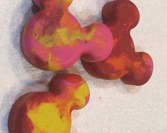 May include: Three colorful Mickey Mouse shaped wax melts in shades of red, yellow, and pink.