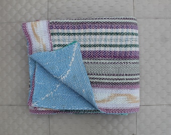 Puede incluir: Un edredón plegado multicolor con rayas horizontales en tonos morado, verde y blanco. El edredón tiene una parte inferior azul claro y está hecho de tela cosida. Los bordes están ribeteados con un borde morado.