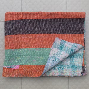 Op de afbeelding: Een veelkleurig kantha-deken met strepen in oranje, groen en blauw. Het deken is gemaakt van gerecyclede sari's en heeft een patchwork-ontwerp.