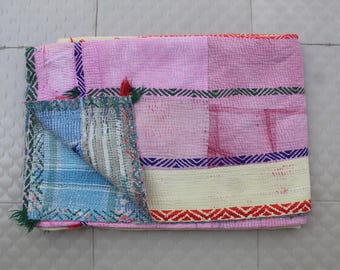 May include: A patchwork quilt with a pink, blue, and white color scheme. The quilt is made of different fabrics and has a hand-stitched look.