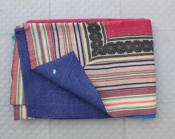 May include: A multi-colored kantha quilt with a blue, pink, and white striped pattern. The quilt has a dark blue fabric on one side and a patchwork of different colored fabrics on the other side.