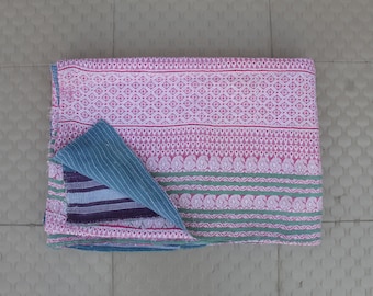 May include: A pink and green kantha quilt with a blue and white patterned fabric folded over the top. The quilt is made of cotton and is hand-stitched.