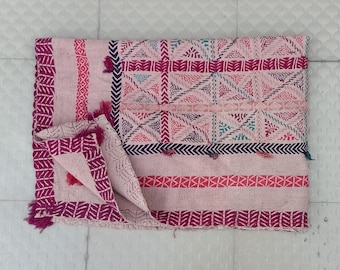 May include: A pink and purple cotton throw blanket with a geometric pattern. The blanket is folded in half and has a fringe border.