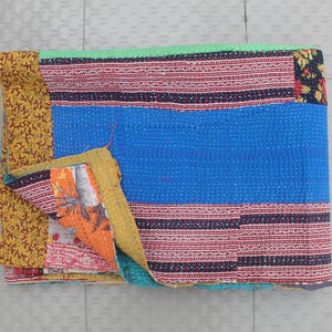 May include: A patchwork quilt in shades of blue, red, and yellow. The central panel is blue, with red and black striped borders. Sections of orange and floral patterns are visible. The quilt is made of stitched fabric.
