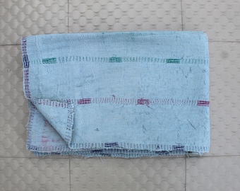 Puede incluir: Textil azul claro doblado con costuras horizontales en verde, morado y azul. Los bordes están acabados con costuras azules más oscuras. Probablemente una manta o un cubrecama.