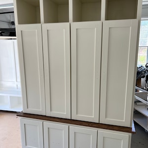 May include: White cabinet with four doors and three open shelves. The cabinet has a wood top and four drawers below the doors.