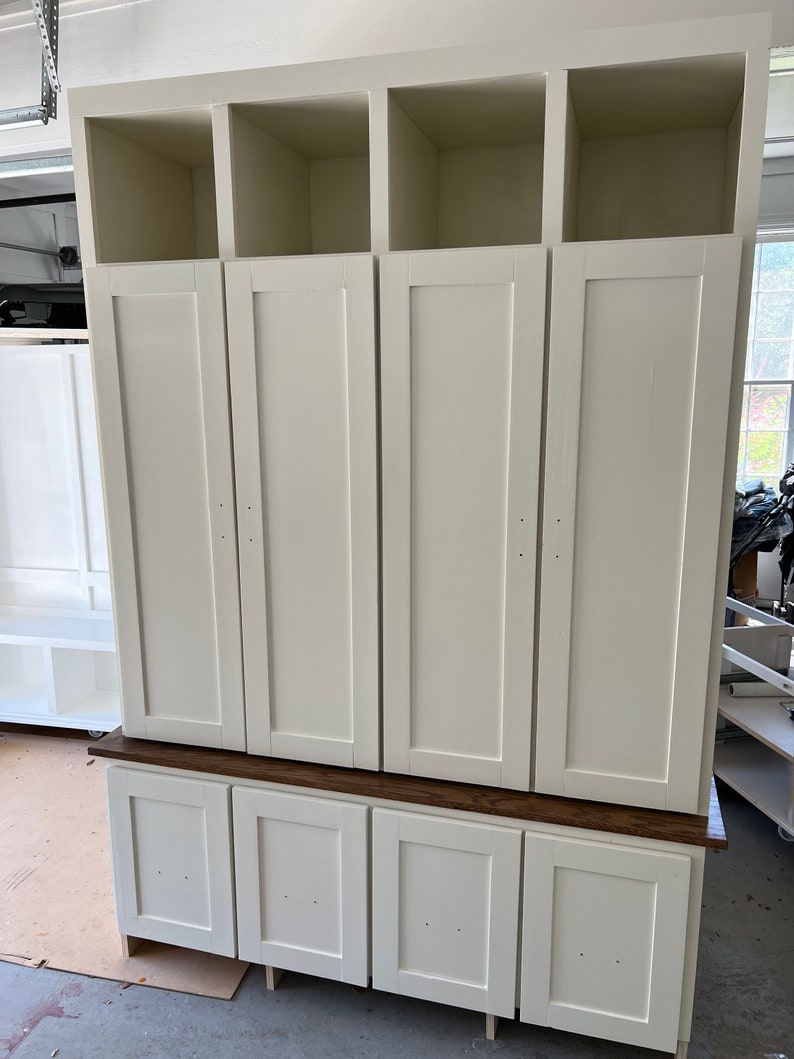 May include: White cabinet with four doors and three open shelves. The cabinet has a wood top and four drawers below the doors.