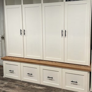 May include: White wooden cabinet with three doors and three drawers. The cabinet has black handles and a wood top.