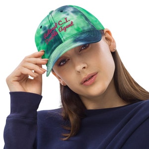 May include: A green and blue tie-dye baseball cap with the text "Retired C.I. Double Agent" embroidered in pink.