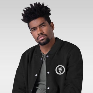 May include: A black varsity jacket with a white embroidered logo of a bearded man's face inside a circle. The jacket has a snap closure and a ribbed collar, cuffs, and waistband.