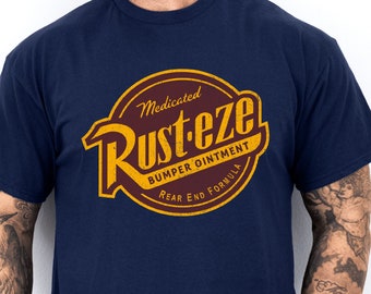May include: A navy blue t-shirt with a vintage-style logo that reads "Medicated Rust-eze Bumper Ointment Rear End Formula". The logo is in yellow and red with a distressed look.