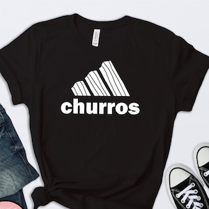 May include: Black t-shirt with a white graphic of a stylized Adidas logo with the word "churro" underneath.