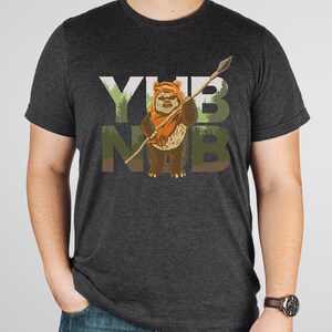 May include: A dark gray t-shirt with a graphic print of a character from Star Wars holding a spear. The text "YUB NUB" is printed on the shirt.