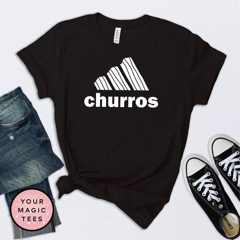 May include: Black t-shirt with a white graphic of a stylized Adidas logo with the word "churro" underneath.