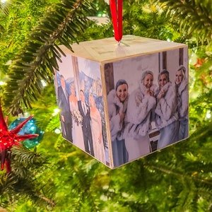 May include: A wooden cube ornament with a photo of four people in winter clothing. The photo is printed on all sides of the cube.