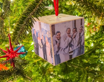 May include: A wooden cube ornament with a photo of four people in winter clothing. The photo is printed on all sides of the cube.