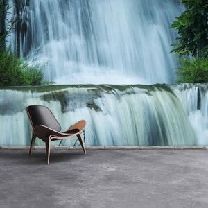 May include: A black leather chair with wooden legs sits in front of a wall mural depicting a waterfall. The waterfall is a blur of white and blue, creating a sense of motion and tranquility.
