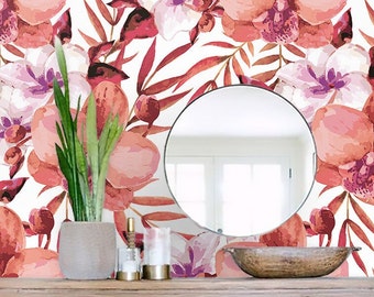 Puede incluir: Una pared blanca con un papel tapiz floral con orquídeas rosas y moradas y hojas rojas. Un espejo redondo cuelga de la pared sobre una mesa consola de madera con un cuenco y velas.
