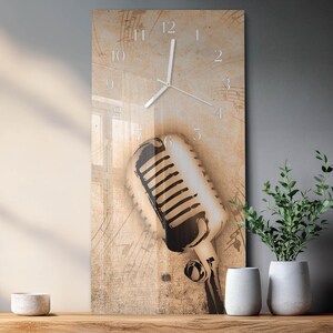 May include: A rectangular wall clock with a vintage microphone design. The clock face has a beige background with musical notes and a large microphone graphic. The clock hands and numbers are silver.
