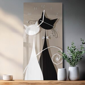 May include: A rectangular wall clock featuring a black and white cat design. The clock face has a neutral beige background with the numbers 1 through 12. The clock hands are white. The cats are stylized with long, elegant lines.