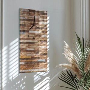 May include: A rectangular wall clock with a wood-look face. The clock face has a pattern of rectangular wooden planks in shades of brown, beige, and gray. Black clock hands and numerals mark the time. The clock is mounted on a white wall.