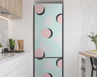 May include: A fridge with a light blue door. The door has a repeating pattern of pink circles, white triangles with dotted fill, and black crescent shapes. The fridge is in a modern kitchen with white cabinets and a marble countertop.