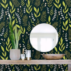 May include: A dark green wallpaper with a repeating pattern of yellow and white leaves and pink flowers. A round mirror hangs on the wall above a wooden console table with a potted plant, candles, and a wooden bowl.