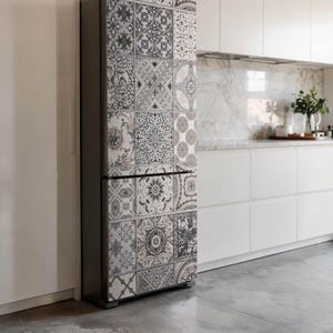Op de afbeelding: Een koelkast met een decoratieve tegelpatroonwikkel. De wikkel heeft een herhalend ontwerp van zwarte, witte en grijze geometrische en bloemmotieven. De koelkast staat in een moderne keuken.