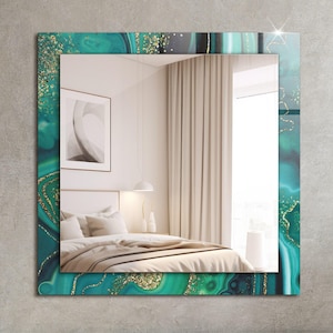 Puede incluir: Un espejo cuadrado con un borde de diseño de ágata verde azulado y dorado. El espejo refleja el interior de un dormitorio con una cama, cortinas blancas y un cuadro en la pared.