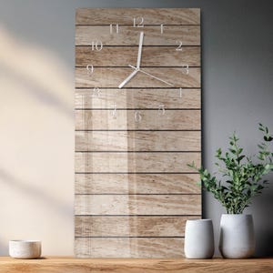 May include: A rectangular wall clock with a wooden plank design. The clock face features white numerals and hands. The clock is mounted on a gray wall, with decorative plants and vases in the foreground.