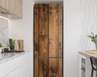 May include: A refrigerator with a wooden panel door. The door is made of vertical planks of dark brown wood with visible grain and knots. The refrigerator is built into a white wall in a modern kitchen.