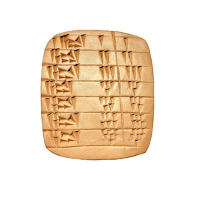 Puede incluir: Una tablilla de arcilla con escritura cuneiforme, un sistema de escritura utilizado en la antigua Mesopotamia. La tablilla es rectangular y tiene un color marrón claro. La escritura está tallada en la superficie de la tablilla.