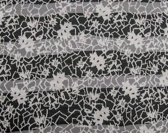 May include: A black and white striped fabric with a repeating pattern of stylized flowers. The fabric has a textured, woven look.