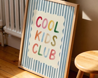 May include: A framed print with the words "COOL KIDS CLUB" in colorful letters. The background has blue and white vertical stripes. A small wooden stool sits nearby on a wooden floor.